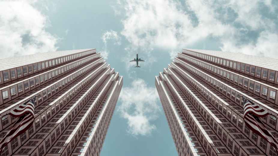 worm s eye view photo of plane between two high rise buildings
